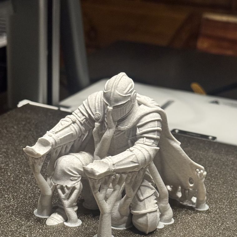 Figura impresa en 3D sobre la cama de la impresora, con los soportes todavía puestos