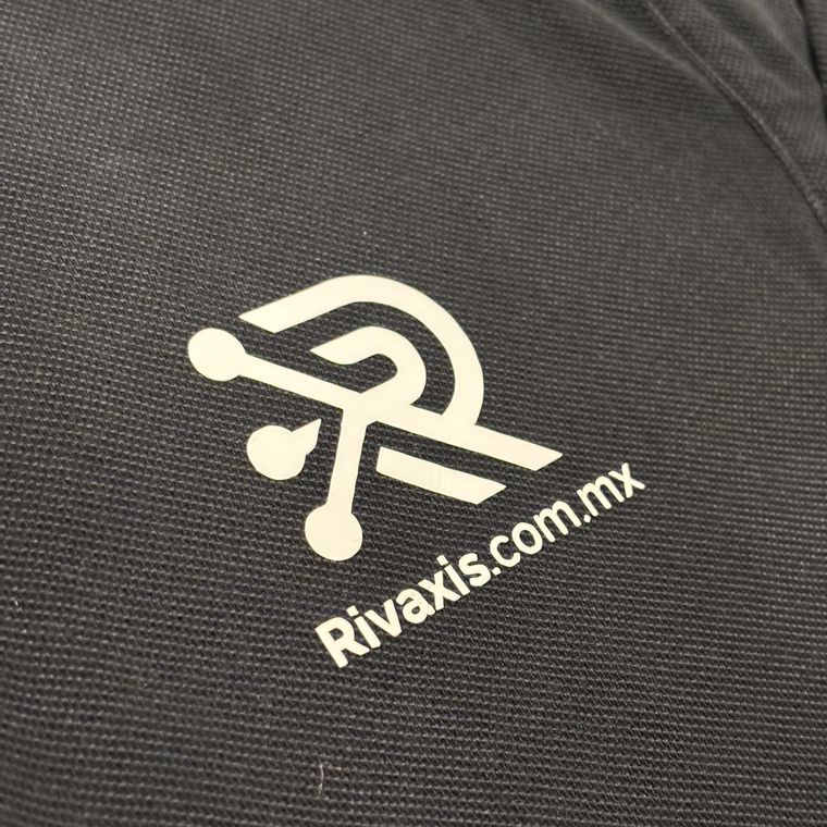 Logo de Rivaxis en vinil textil blanco sobre un polo oscuro